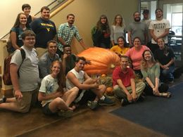 group of students posing around gigantic pumpkin