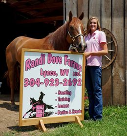 Randi Dove and a horse standing in front of her Randi Dove Farms sign that is advertising boardings, training, lessons, parties & events