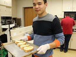 Student holding a tray of baked goods